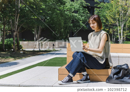 Female college student using a laptop outdoors Female college student using a laptop outdoors 102398712