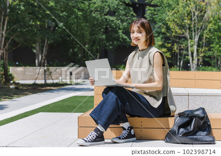 Female college student using a laptop outdoors Female college student using a laptop outdoors 102398714