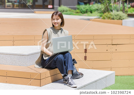 Female college student using a laptop outdoors Female college student using a laptop outdoors 102398724
