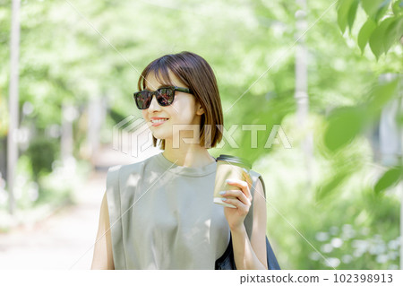 Young woman wearing sunglasses walking in fresh green Young woman wearing sunglasses walking in fresh green 102398913