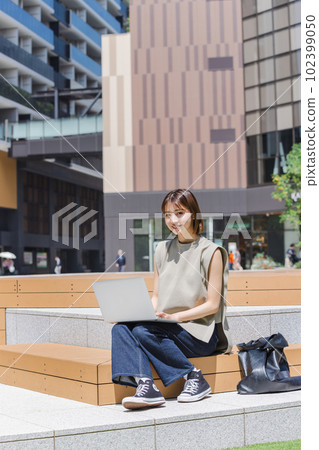 Female college student using a laptop outdoors Female college student using a laptop outdoors 102399050