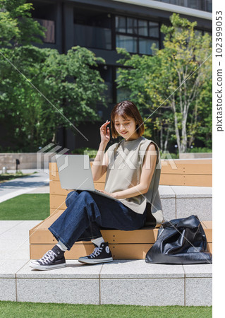 Female college student using a laptop outdoors Female college student using a laptop outdoors 102399053