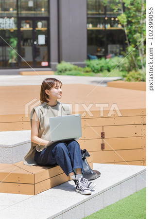 Female college student using a laptop outdoors Female college student using a laptop outdoors 102399056