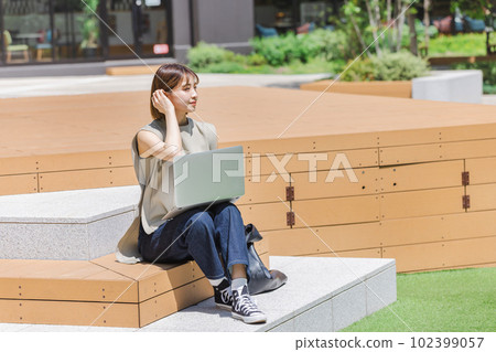 Female college student using a laptop outdoors Female college student using a laptop outdoors 102399057