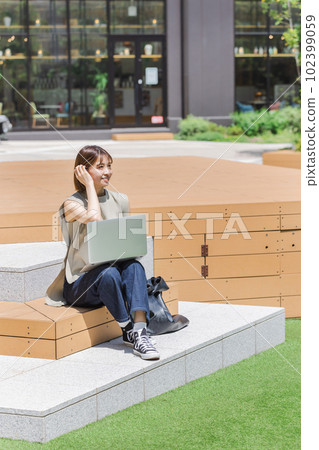 Female college student using a laptop outdoors Female college student using a laptop outdoors 102399059