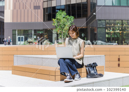Female college student using a laptop outdoors Female college student using a laptop outdoors 102399140