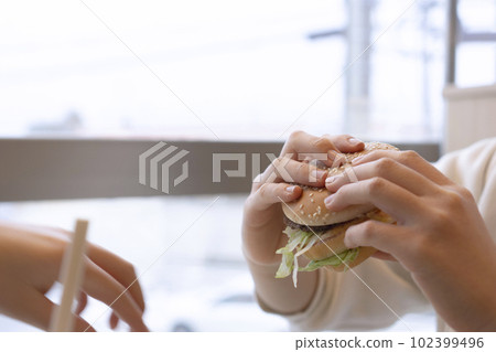 A girl who eats a hamburger A girl who eats a hamburger 102399496