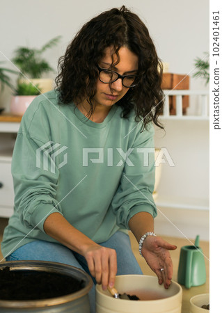 Woman grows potted plants at home watering and take care flowers - gardening and houseplant care concept Woman grows potted plants at home watering and take care flowers - gardening and houseplant care concept 102401461