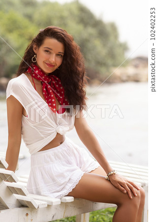 Tourist Woman in Summer Stylish Outfit on a Beach Chair During Vacations Tourist Woman in Summer Stylish Outfit on a Beach Chair During Vacations 102402253