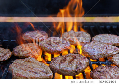 Grilled American beef burger barbecued over hot grill on flames of grill Grilled American beef burger barbecued over hot grill on flames of grill 102403404
