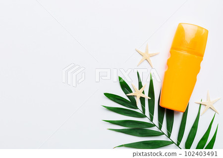 Sunscreen spray bottle. Bottle with sun protection cream and sea shells with tropical green leaf on color background, top view Sunscreen spray bottle. Bottle with sun protection cream and sea shells with tropical green leaf on color background, top view 102403491