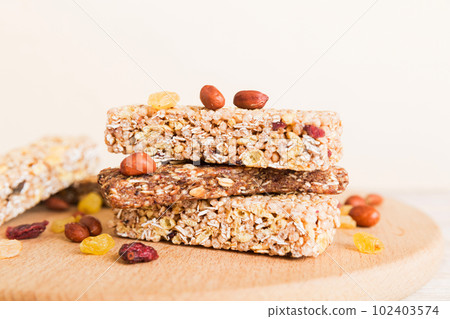 Various granola bars on table background. Cereal granola bars. Superfood breakfast bars with oats, nuts and berries, close up. Superfood concept Various granola bars on table background. Cereal granola bars. Superfood breakfast bars with oats, nuts and berries, close up. Superfood concept 102403574