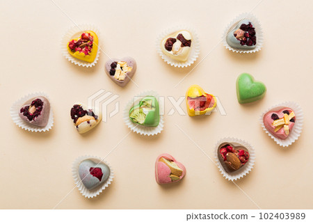 chocolate sweets in the form of a heart with fruits and nuts on a colored background. top view with space for text, holiday concept chocolate sweets in the form of a heart with fruits and nuts on a colored background. top view with space for text, holiday concept 102403989