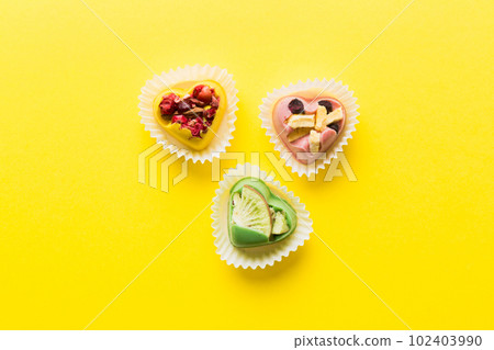 chocolate sweets in the form of a heart with fruits and nuts on a colored background. top view with space for text, holiday concept chocolate sweets in the form of a heart with fruits and nuts on a colored background. top view with space for text, holiday concept 102403990