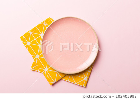 Top view on colored background empty round pink plate on tablecloth for food. Empty dish on napkin with space for your design Top view on colored background empty round pink plate on tablecloth for food. Empty dish on napkin with space for your design 102403992