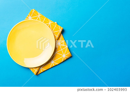 Top view on colored background empty round yellow plate on tablecloth for food. Empty dish on napkin with space for your design 102403993