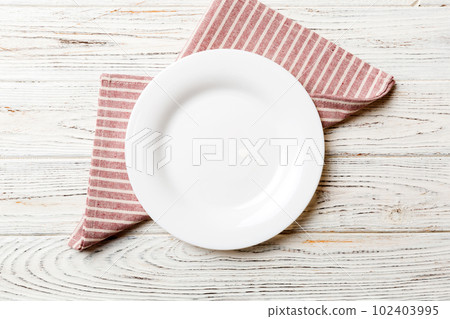 Top view on colored background empty round white plate on tablecloth for food. Empty dish on napkin with space for your design Top view on colored background empty round white plate on tablecloth for food. Empty dish on napkin with space for your design 102403995