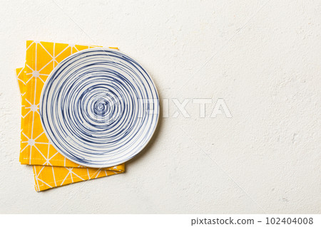 Top view on colored background empty round blue plate on tablecloth for food. Empty dish on napkin with space for your design Top view on colored background empty round blue plate on tablecloth for food. Empty dish on napkin with space for your design 102404008
