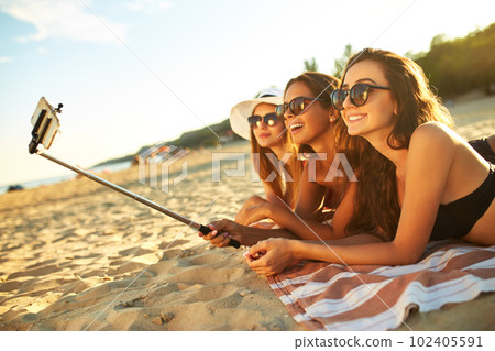 Summer holidays and vacation - girls sunbathing on the beach.girls doing selfie phone. enjoy summer time. 102405591