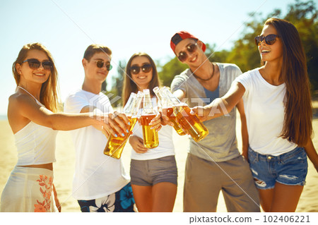 Group of friends hanging out with beer at the beach. Excellent sunny weather. Beautiful figures. 102406221