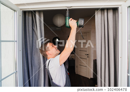 A repairman repairs or adjusts window frames or glass doors on the terrace. 102406478