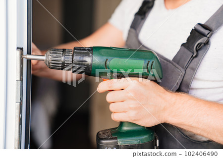 A repairman repairs or adjusts window frames or glass doors on the terrace. 102406490