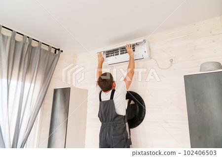A man replaces and cleans the air cleaner filter from the air conditioner. 102406503