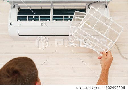 A man replaces and cleans the air cleaner filter from the air conditioner. A man replaces and cleans the air cleaner filter from the air conditioner. 102406506