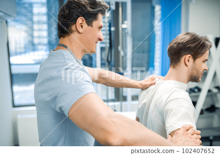 Male physical therapist working with a patient and looking invloved Male physical therapist working with a patient and looking invloved 102407652