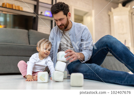 Bearded father playing with toddler child on floor with cubes. Bearded father playing with toddler child on floor with cubes. 102407676