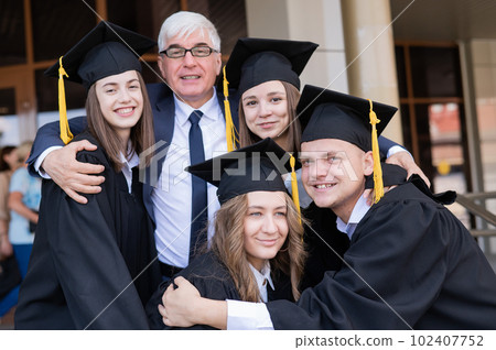 A gray-haired male teacher congratulates students on their graduation from the university. A gray-haired male teacher congratulates students on their graduation from the university. 102407752