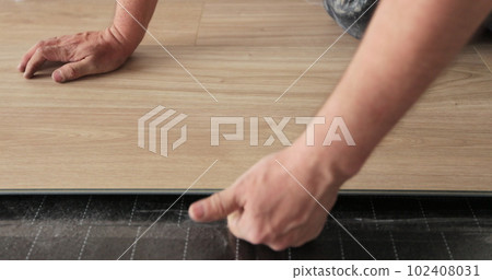 Close-up of a man in an apartment laying laminate on the floor. Floor in a Home. Closeup on male hands. 102408031