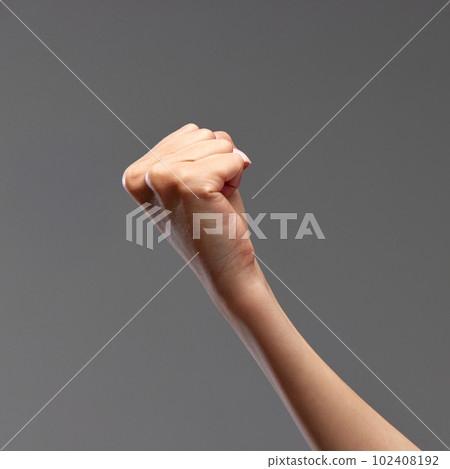 Female hand showing fist against grey background. Freedom of speech, equality, fighting against wrong situations 102408192