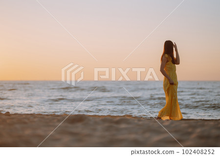Young woman walks along seashore at sunset. Nature, relax, lifestyle concept. 102408252