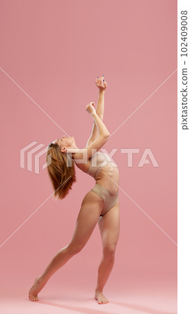 Portrait of one emotional young girl with silk hair wearing beige underwear posing over pink studio background. Hair care products Portrait of one emotional young girl with silk hair wearing beige underwear posing over pink studio background. Hair care products 102409008