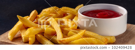 French fries panorama, potato snack with ketchup, fast food on black French fries panorama, potato snack with ketchup, fast food on black 102409428