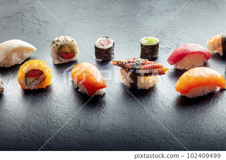Sushi on a black slate plate. Nigiri with eel, salmon and tuna, roll etc Sushi on a black slate plate. Nigiri with eel, salmon and tuna, roll etc 102409499