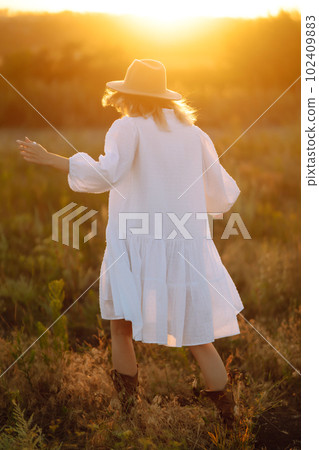 Fashionably dressed woman on the sunset or sunrise in summer nature. Fashion, glamour, lifestyle concept. 102409883