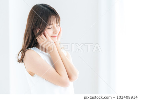 Young woman doing skin care by the window in the living room Young woman doing skin care by the window in the living room 102409914