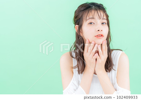 Young woman doing skin care on green background 102409933