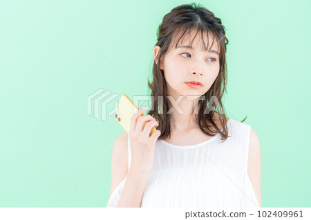 A young woman operating a smartphone on a green background 102409961