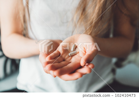 Close up two vitamin pills on the palm of unrecognizable woman hand Close up two vitamin pills on the palm of unrecognizable woman hand 102410473