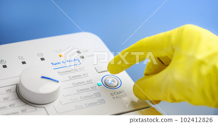 Finger in yellow glove about to press button switch on atomatic washing machine Finger in yellow glove about to press button switch on atomatic washing machine 102412826