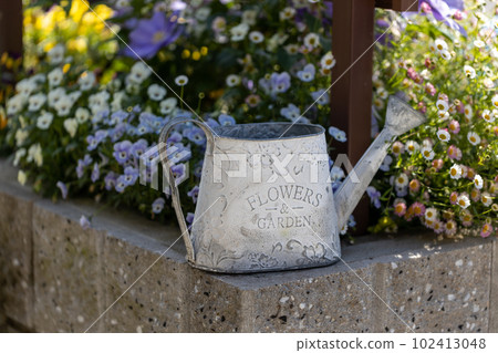 A white watering can in the garden 102413048