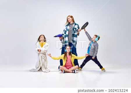 Domestic lifestyle. Portrait of young woman, other and little kids, children posing in home wear against grey studio background 102413224