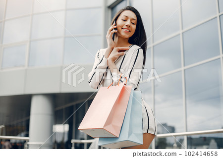 Beautiful girl in a summer city. Lady with shopping bags 102414658