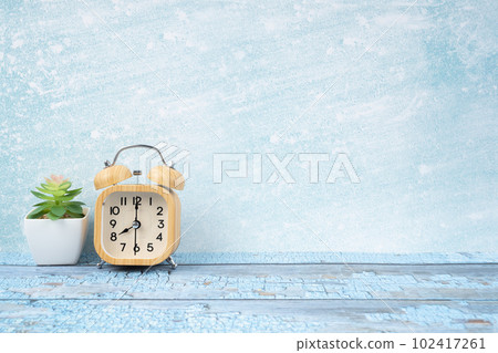 The Wooden alarm clock and plant pot on blue wooden floor with copy space for your design. 102417261