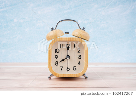 The Wooden alarm clock on wooden floor with blue wall. The Wooden alarm clock on wooden floor with blue wall. 102417267
