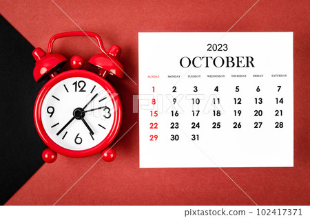 The October 2023 Monthly calendar year with alarm clock on red and black background. 102417371
