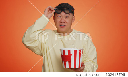 Excited man in 3D glasses eating popcorn and watching interesting tv serial, sport game film movie Excited man in 3D glasses eating popcorn and watching interesting tv serial, sport game film movie 102417796